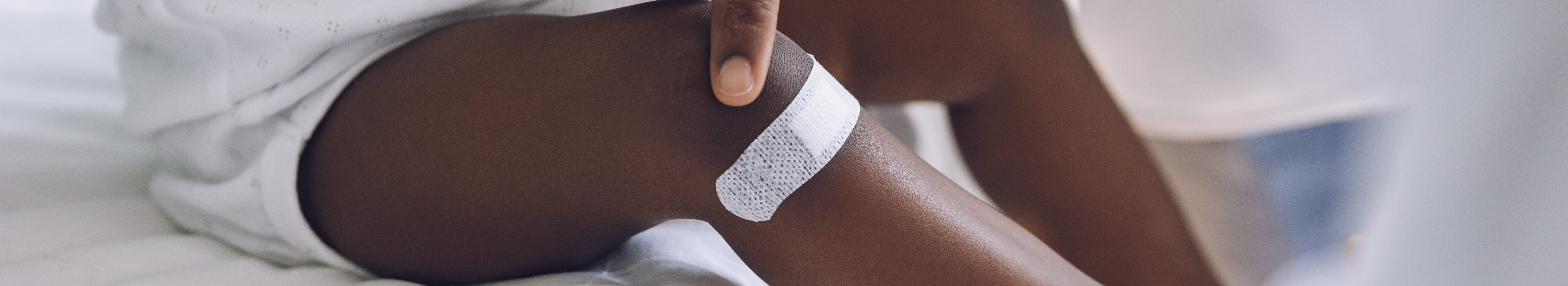 Petit enfant avec pigmentation portant un pansement adhésif sur la jambe